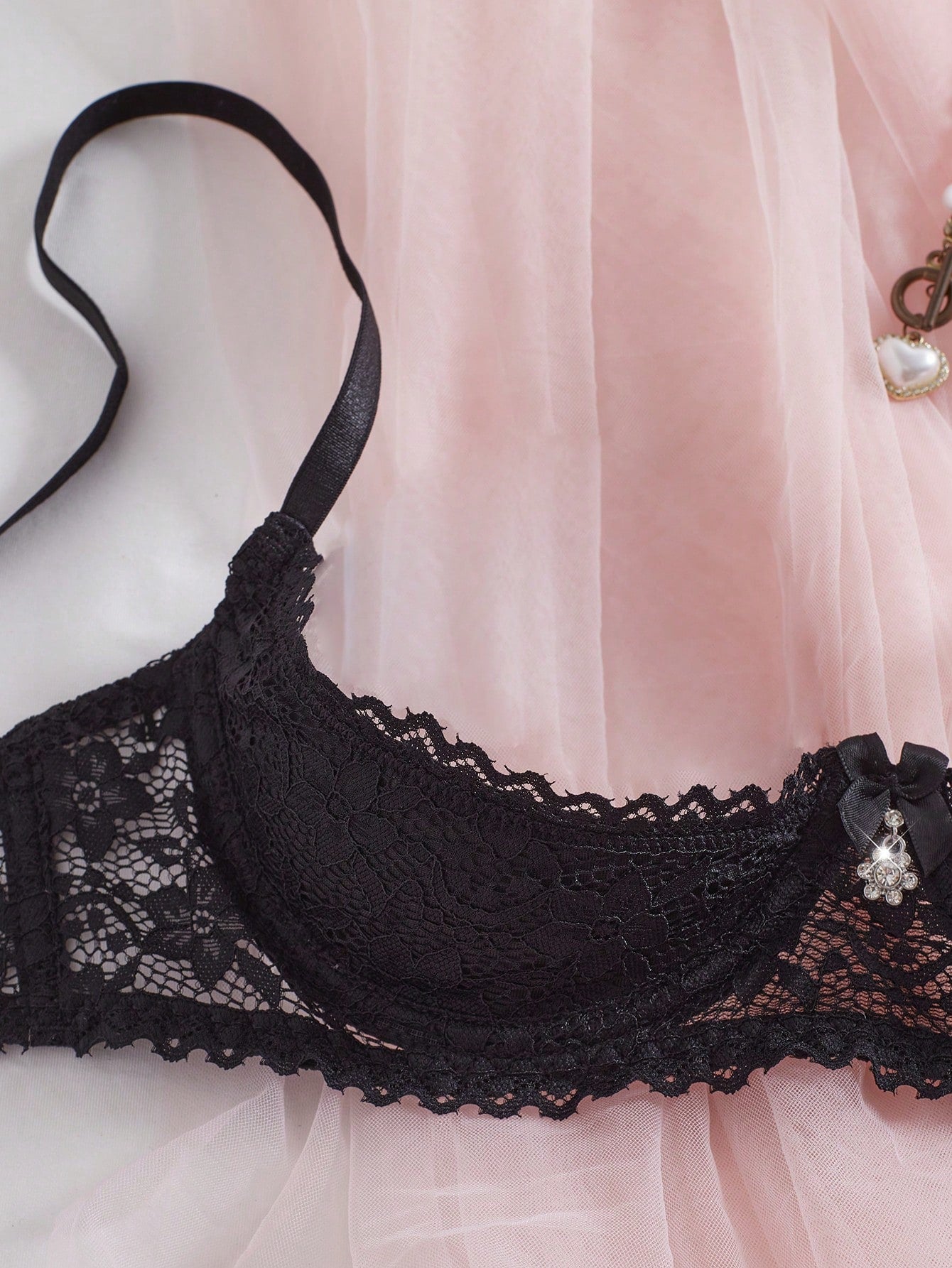 Women's semi-sheer black lace underwire bra with adjustable spaghetti straps, contrast lace detail, 1/2 cup design, and pullover fit.