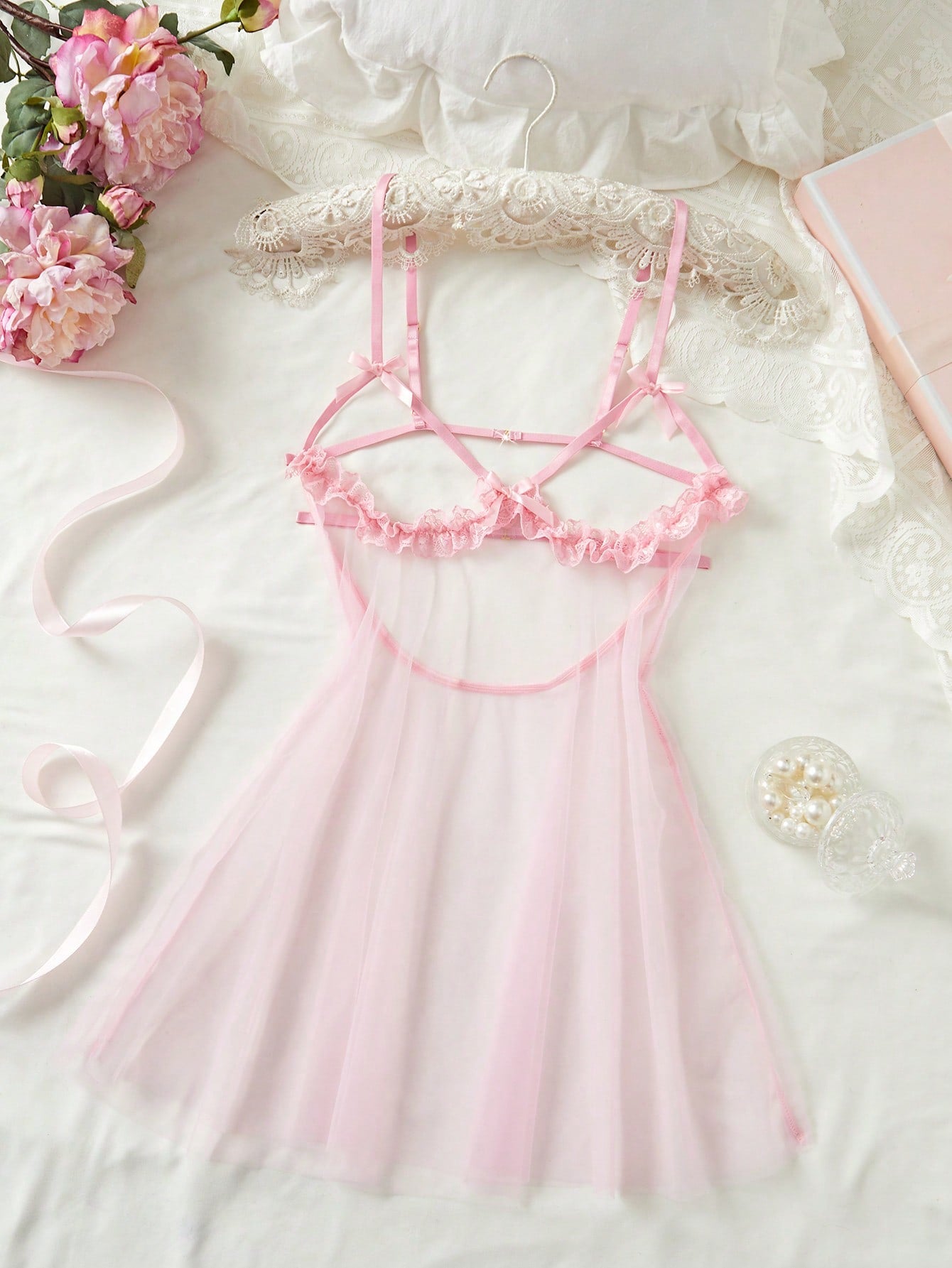 Women's baby pink babydoll nightgown with sheer backless design, bow detail, plunge neckline, adjustable straps, and short slip silhouette.