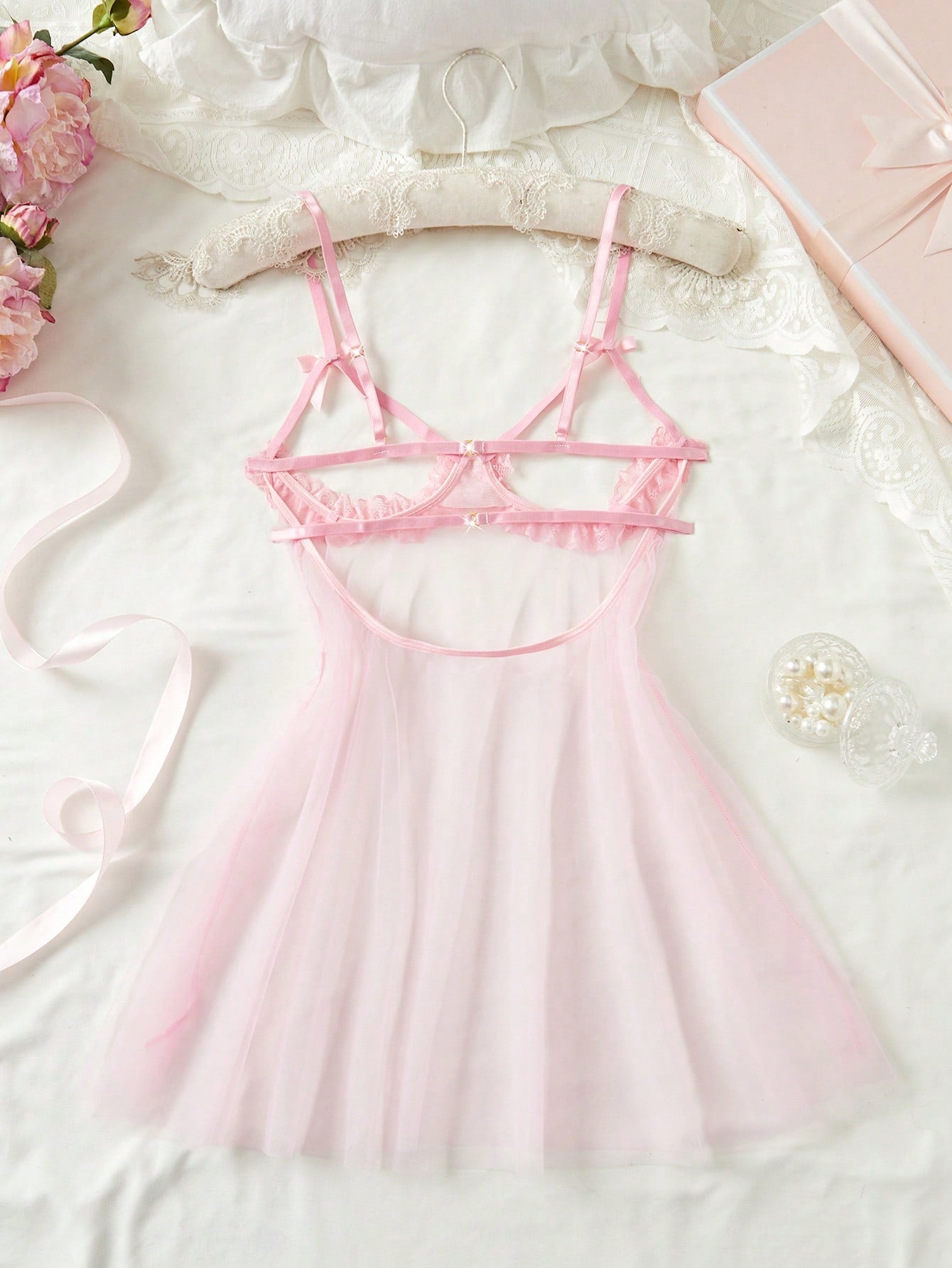 Women's baby pink babydoll nightgown with sheer backless design, bow detail, plunge neckline, adjustable straps, and short slip silhouette.