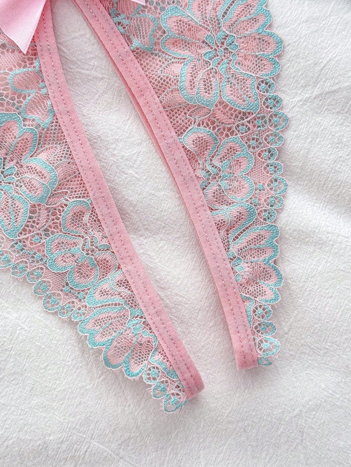 Sheer pink knitted lingerie set for women with a wireless triangle bralette, adjustable spaghetti straps, bow detail, backless design, and matching low-rise briefs.
