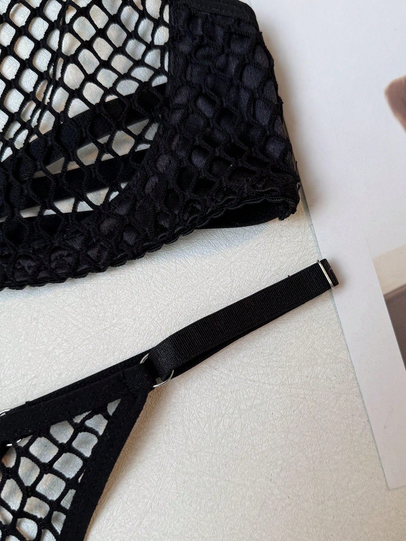 Black women's fishnet lingerie set with hollow out detail, halter underwire top, and low-rise thong in sheer mesh fabric.