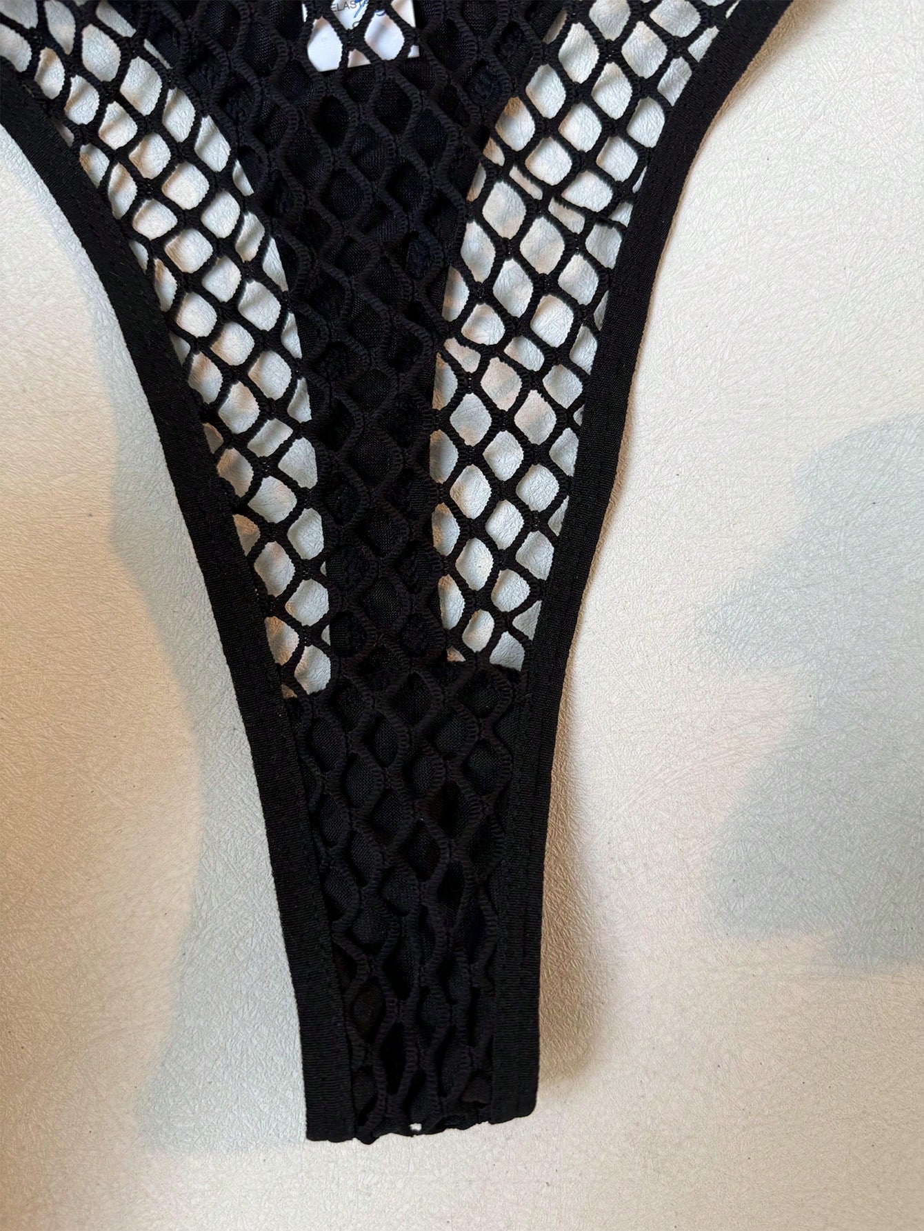 Black women's fishnet lingerie set with hollow out detail, halter underwire top, and low-rise thong in sheer mesh fabric.