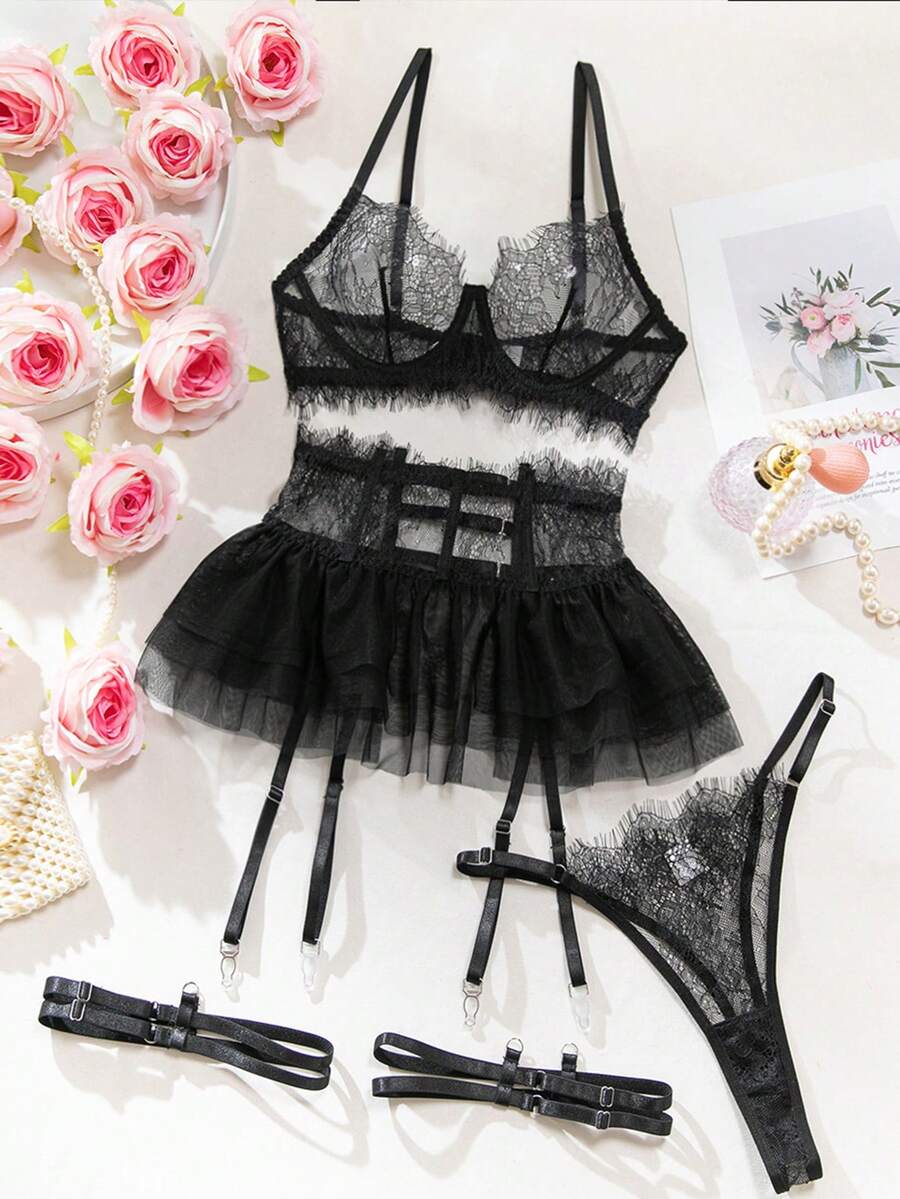 Front view of a 5-piece black lace lingerie set featuring an underwire bra with contrast mesh, matching garter belt, ruffle skirt, and high-rise thong.