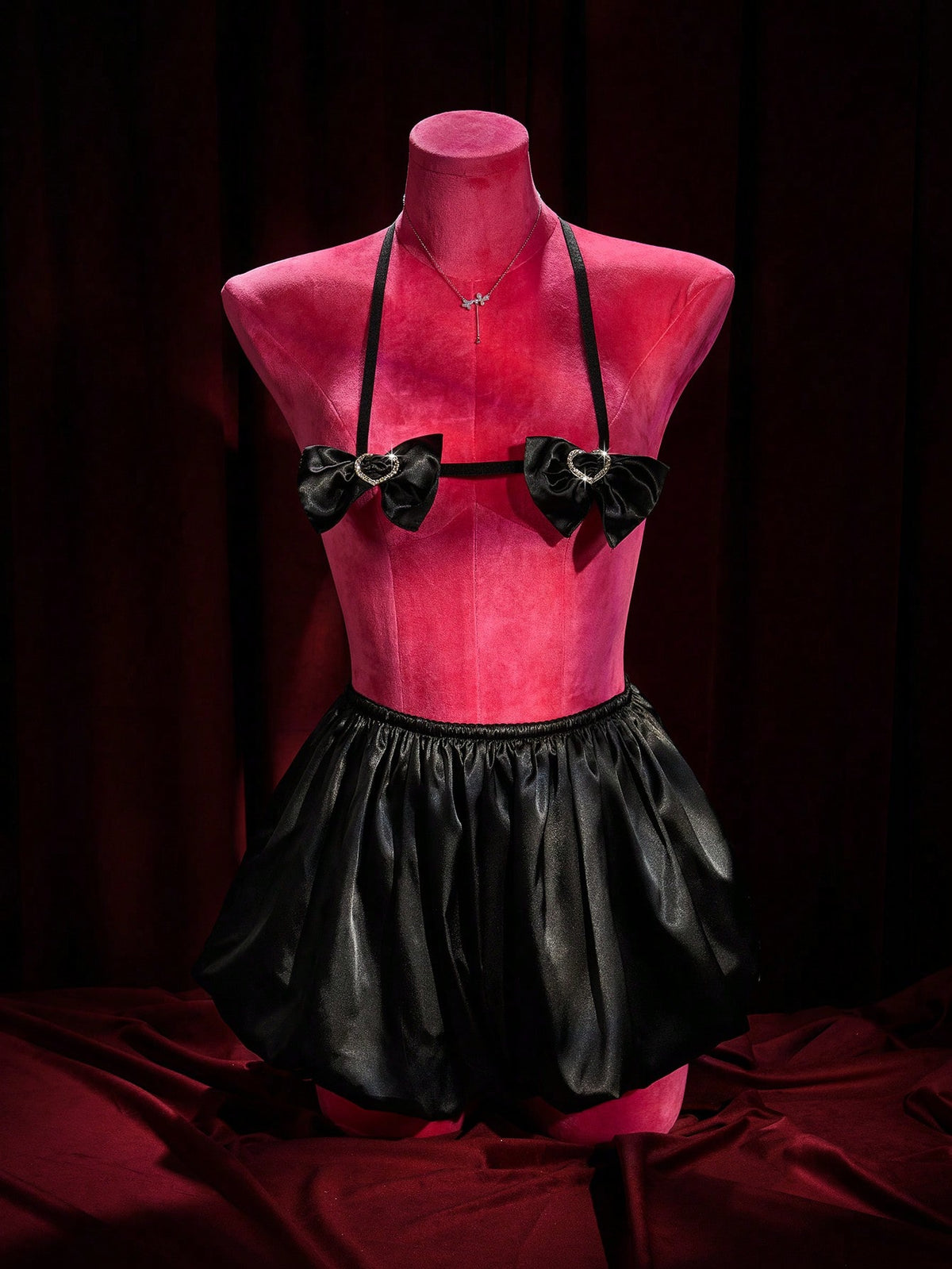 A 2-piece women's black gothic lingerie set featuring a halter bralette top with bow tie and heart detail paired with matching ruffled mid-rise boyshorts.