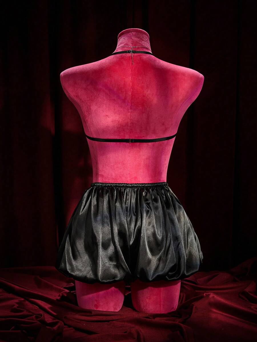 A 2-piece women's black gothic lingerie set featuring a halter bralette top with bow tie and heart detail paired with matching ruffled mid-rise boyshorts.