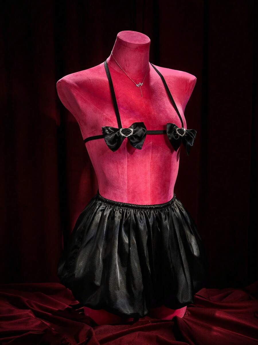A 2-piece women's black gothic lingerie set featuring a halter bralette top with bow tie and heart detail paired with matching ruffled mid-rise boyshorts.