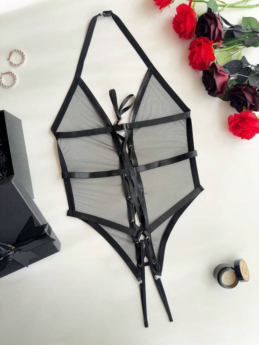 Black halter lingerie bodysuit featuring criss-cross lace-up front details, adjustable shoulder straps, and a low rise thong design.