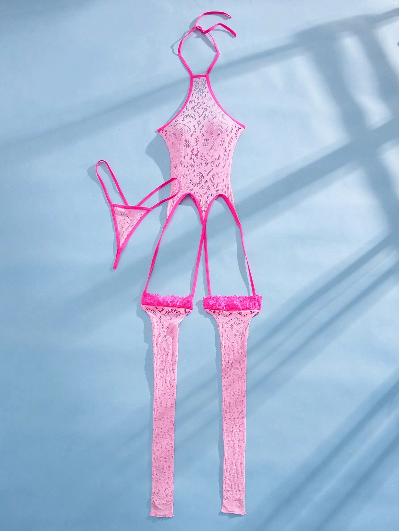 Women's semi-sheer mesh lingerie bodysuit set with halter neckline, backless design, hollow out details, bow accent, and thong styling in pink colorblock fabric.