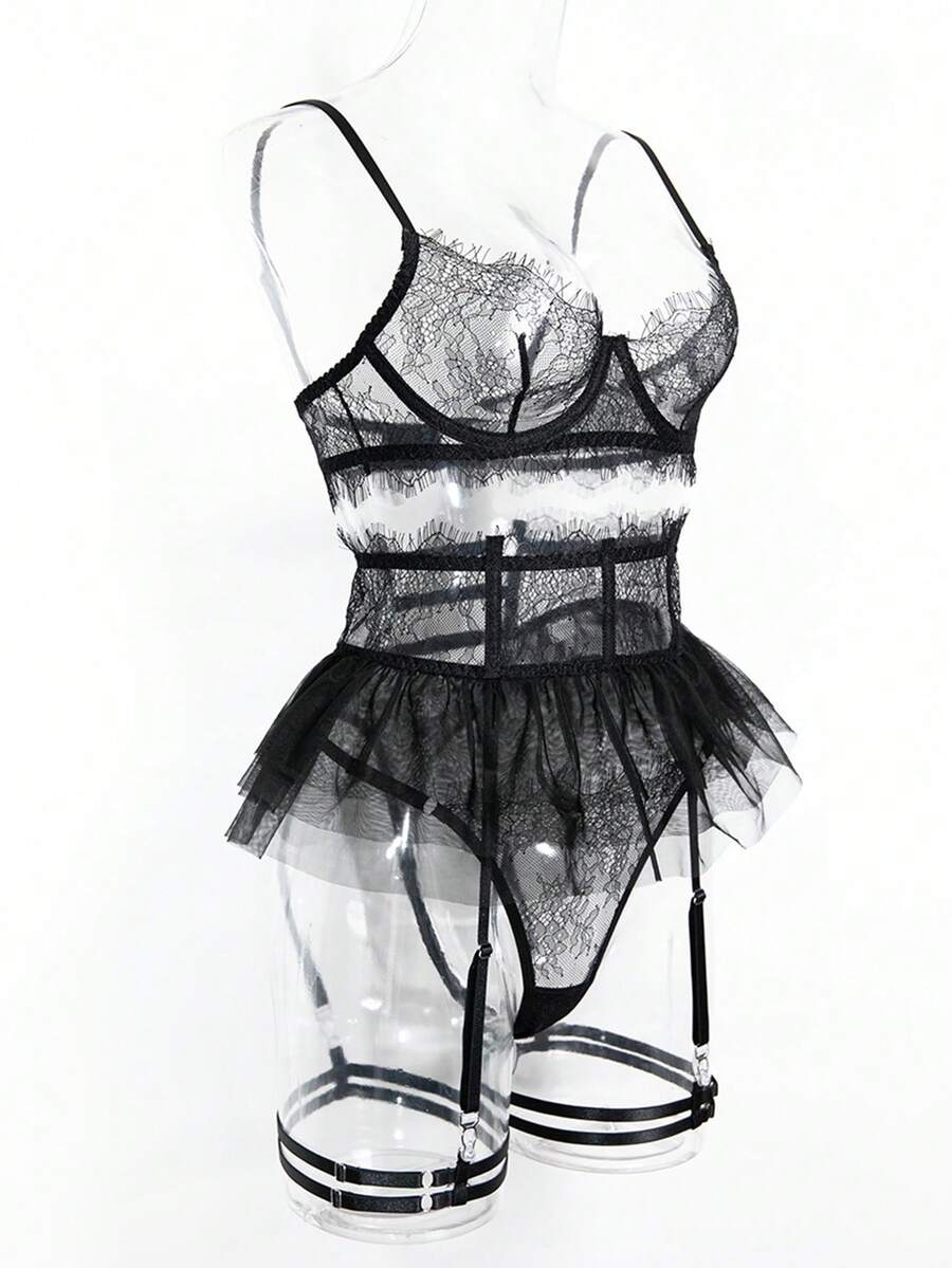 Front view of a 5-piece black lace lingerie set featuring an underwire bra with contrast mesh, matching garter belt, ruffle skirt, and high-rise thong.