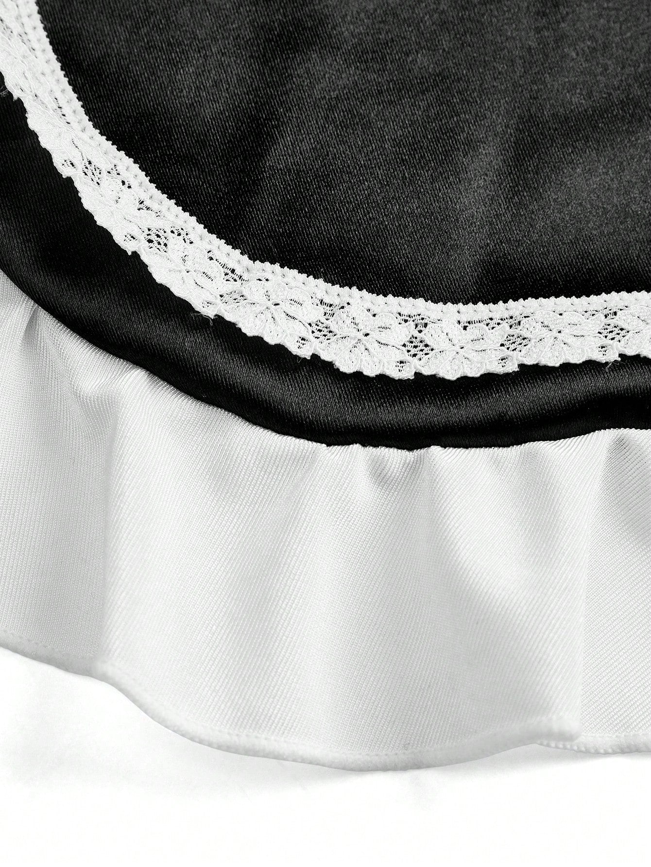 Women's black and white colorblock lingerie set with a backless ruffled teddy design, adjustable spaghetti straps, wireless fit, and thong-style bottom.