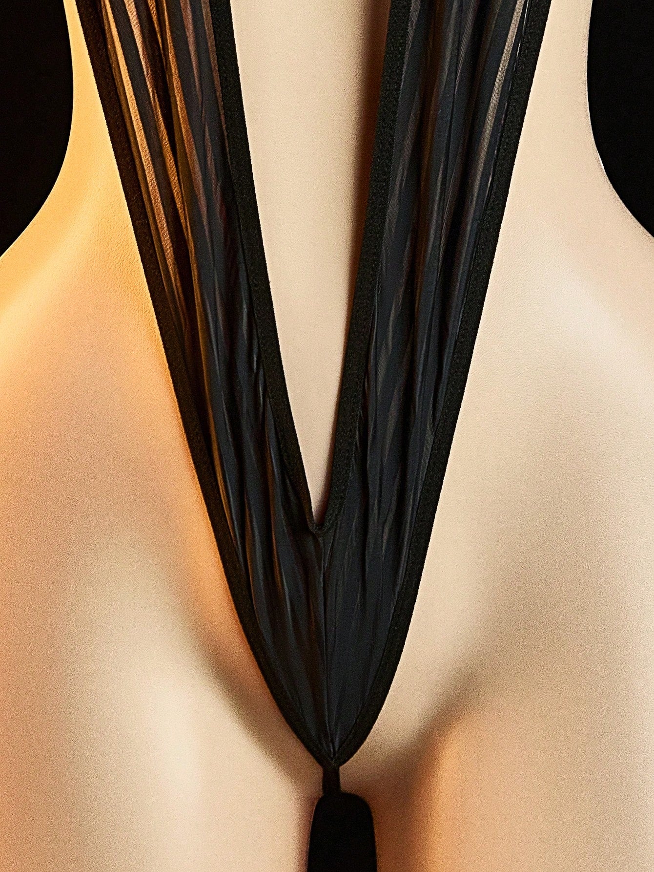 Women's sheer black lace bodysuit with backless design, halter neckline, and wireless one-piece fit in medium-stretch knitted fabric.
