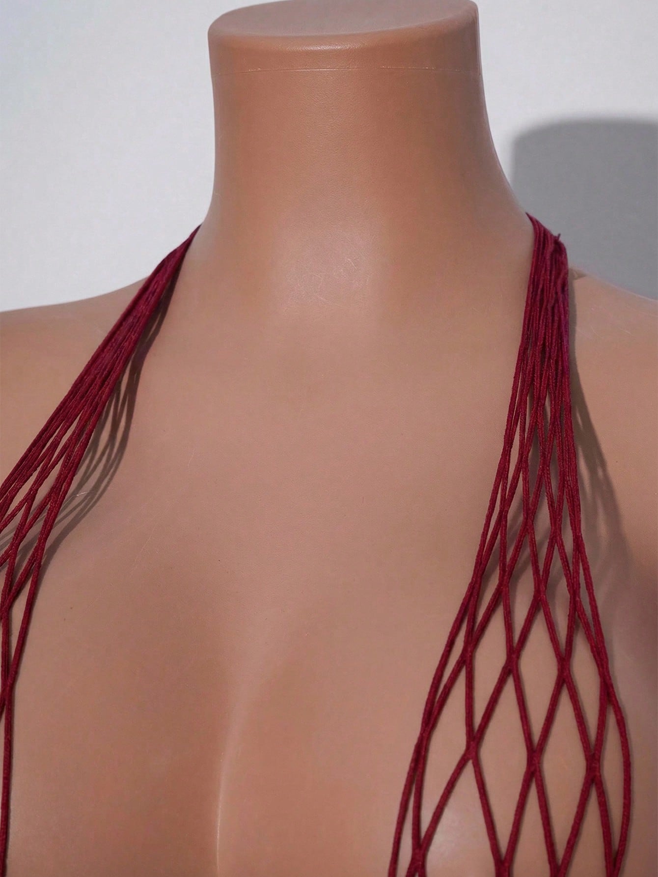 Women's burgundy sheer fishnet bodysuit with halter neckline, lace-up hollow out details, adjustable straps, and sleeveless Y2K styling.