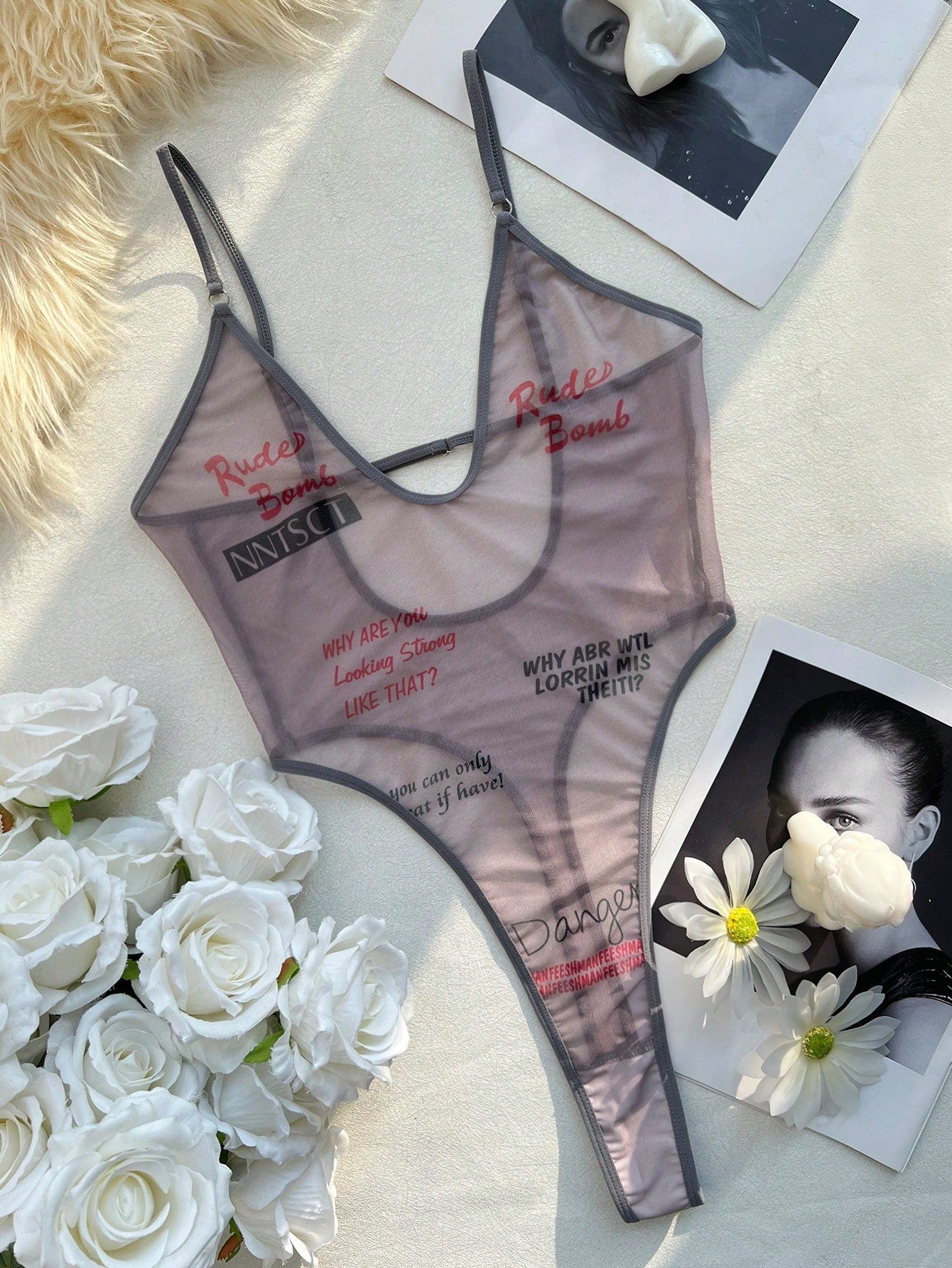 Women's sheer mesh lingerie jumpsuit in grey with a deep V neckline, adjustable straps, thong cut, and high-stretch one-piece design.