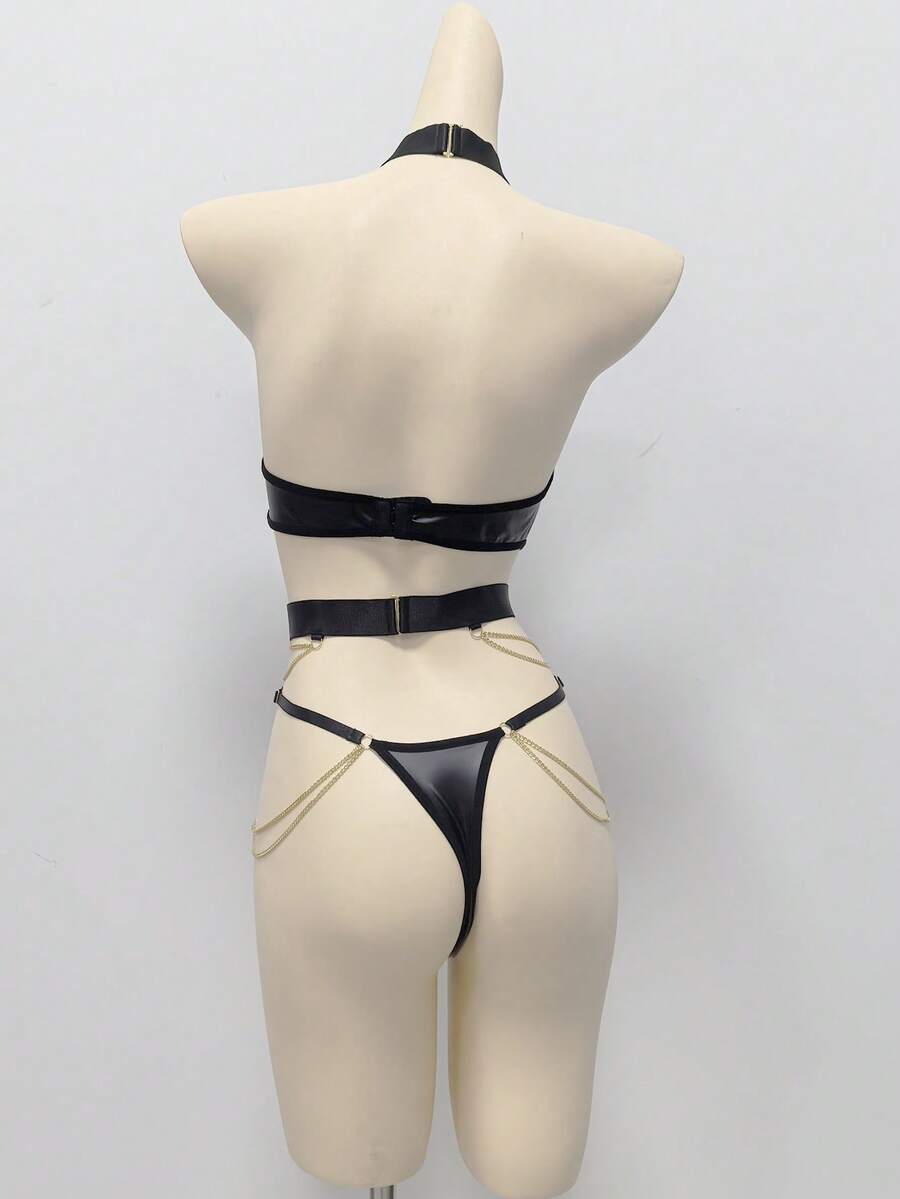 Front view of a women's black PU leather halter teddy bodysuit with cut-out details, metallic chain accents, and ring hardware.