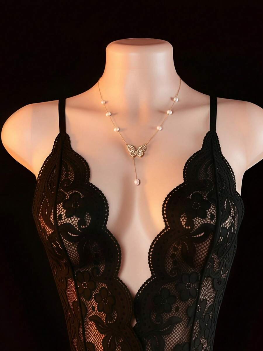 Women's black lace jumpsuit lingerie featuring adjustable spaghetti straps, low cut neckline with bow detail, and sheer medium stretch fabric.