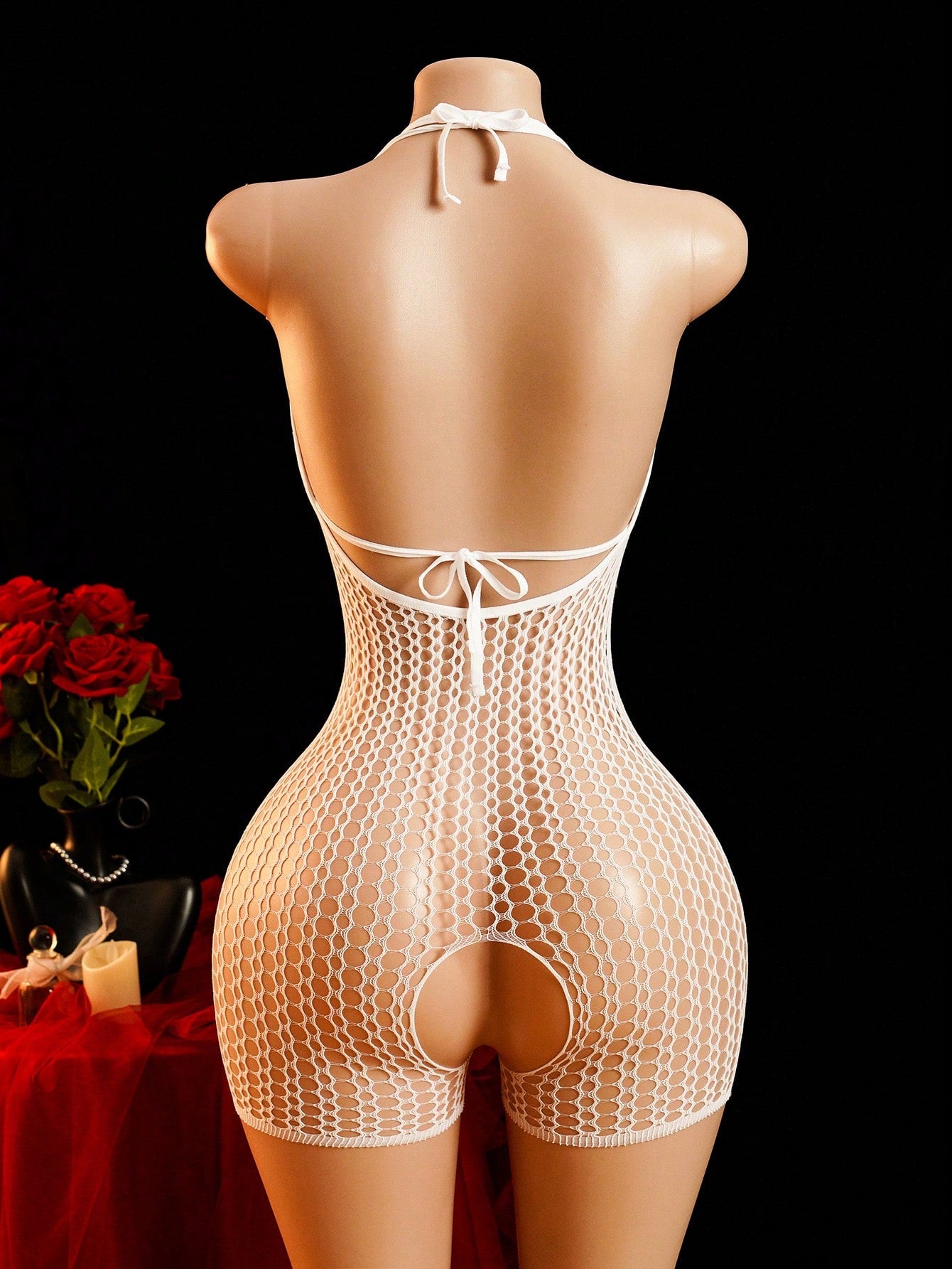 Women's sheer fishnet lingerie set with halter-style top, short bodysuit silhouette, adjustable straps, hollow out details, bow accent, and V-string bottom.