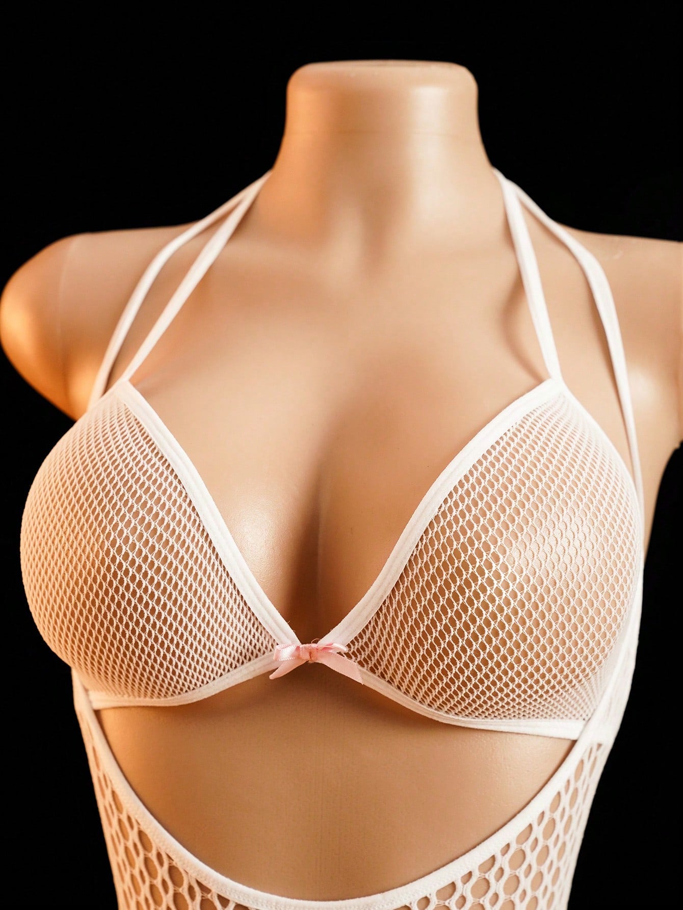 Women's sheer fishnet lingerie set with halter-style top, short bodysuit silhouette, adjustable straps, hollow out details, bow accent, and V-string bottom.