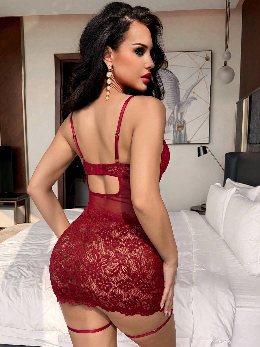 Woman wearing a sheer black lace patchwork mesh nightgown featuring underwire cups, adjustable spaghetti straps, matching thong, and leg rings.