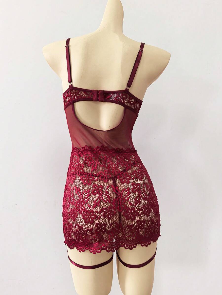 Woman wearing a sheer black lace patchwork mesh nightgown featuring underwire cups, adjustable spaghetti straps, matching thong, and leg rings.