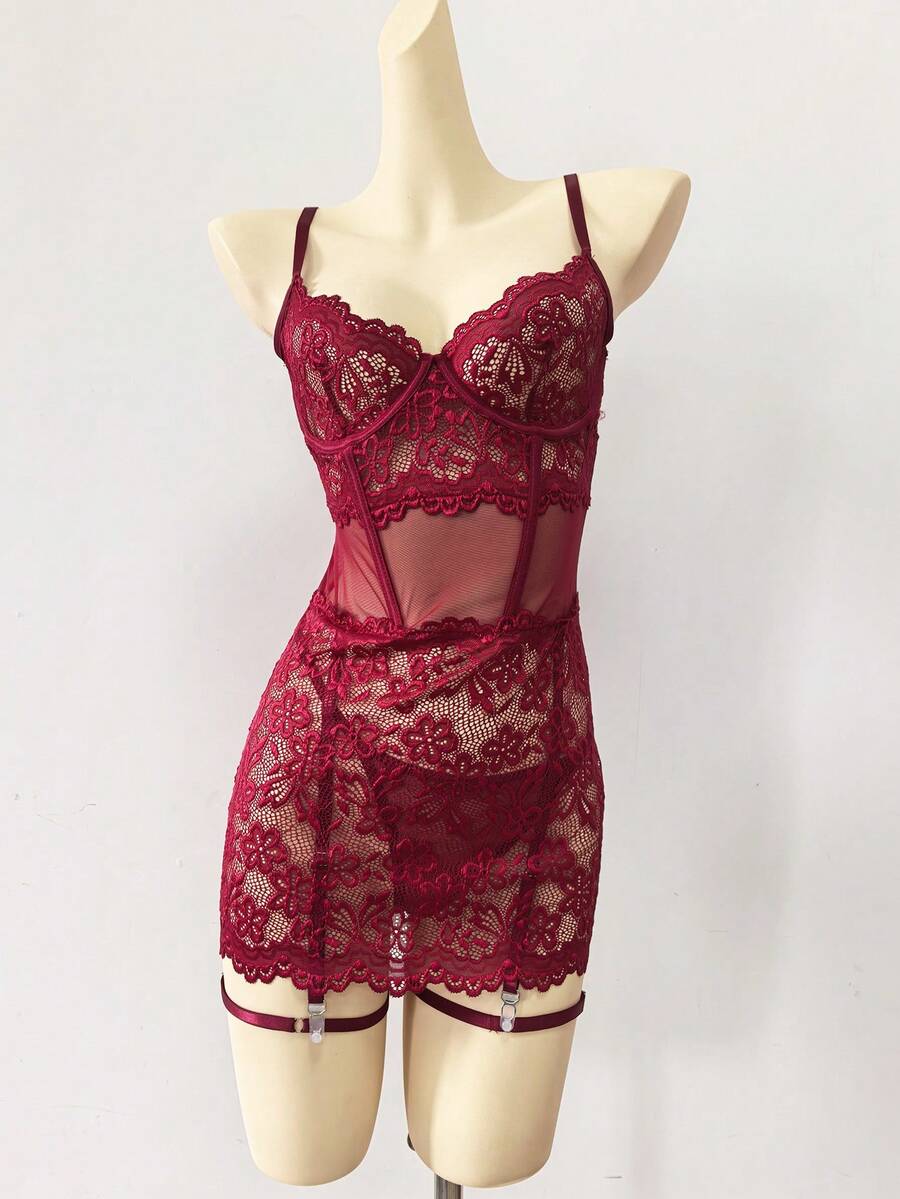 Woman wearing a sheer black lace patchwork mesh nightgown featuring underwire cups, adjustable spaghetti straps, matching thong, and leg rings.