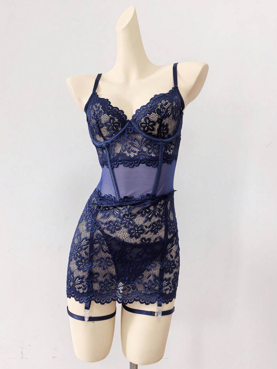 Woman wearing a sheer black lace patchwork mesh nightgown featuring underwire cups, adjustable spaghetti straps, matching thong, and leg rings.