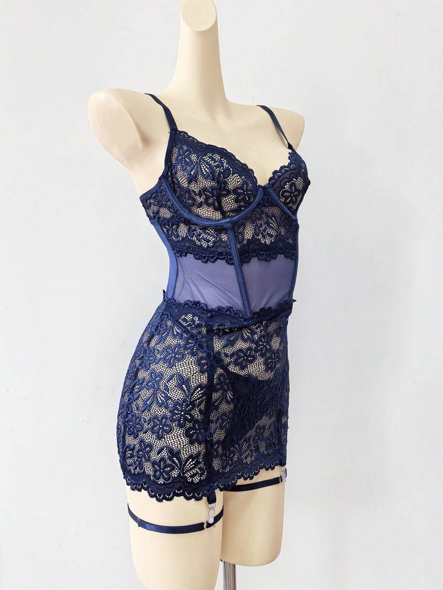 Woman wearing a sheer black lace patchwork mesh nightgown featuring underwire cups, adjustable spaghetti straps, matching thong, and leg rings.